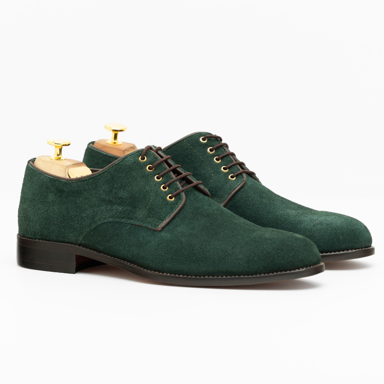Green suede shoes with brown laces on a white background