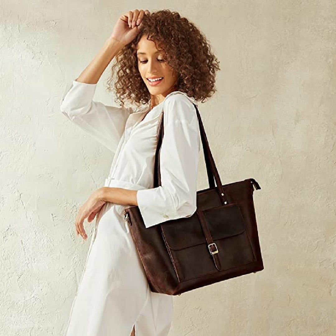 Woman holding a brown leather bag against a plain background