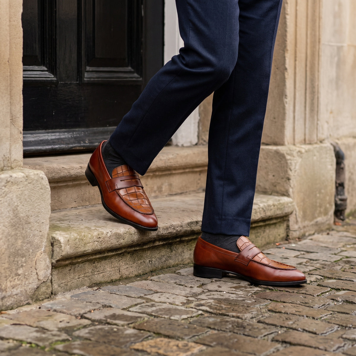 The Brook men's penny loafer in brown alligator-texture calf leather, styled editorial photo