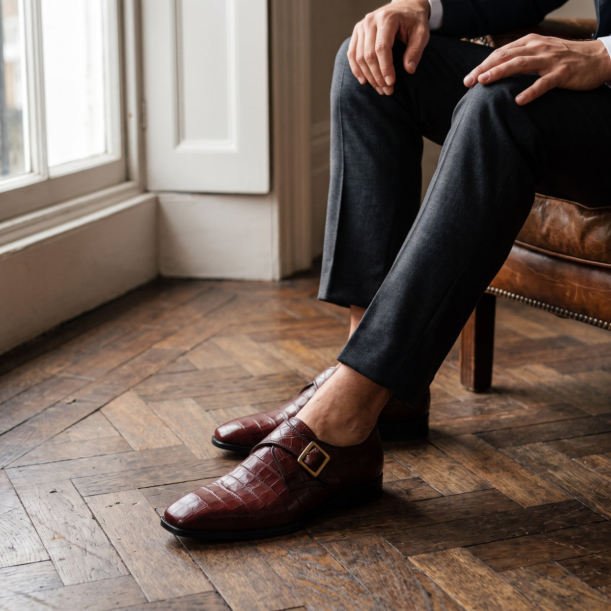 The Ogden men's monk strap shoe in burgundy alligator-texture calf leather with patina finish, styled editorial photo