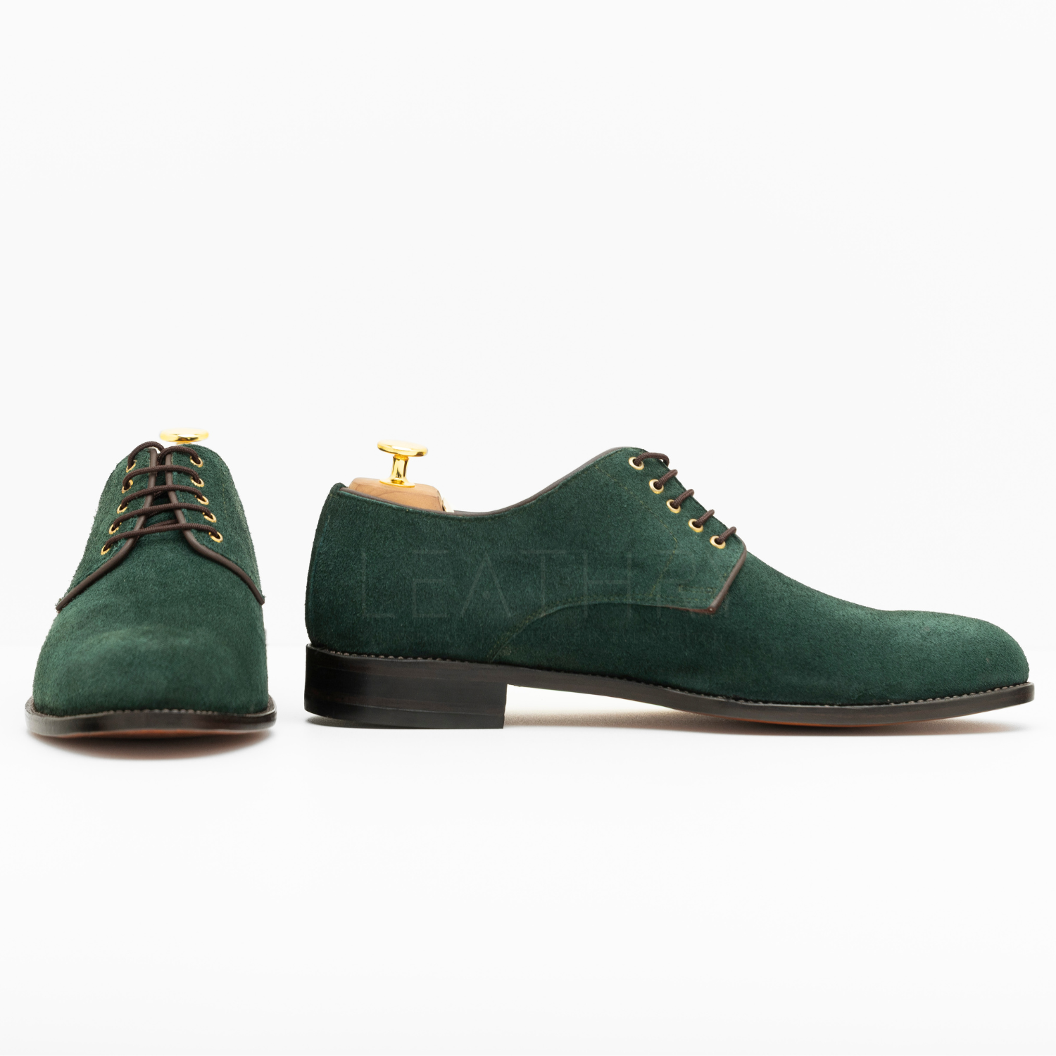 Green suede shoes with gold laces on a white background