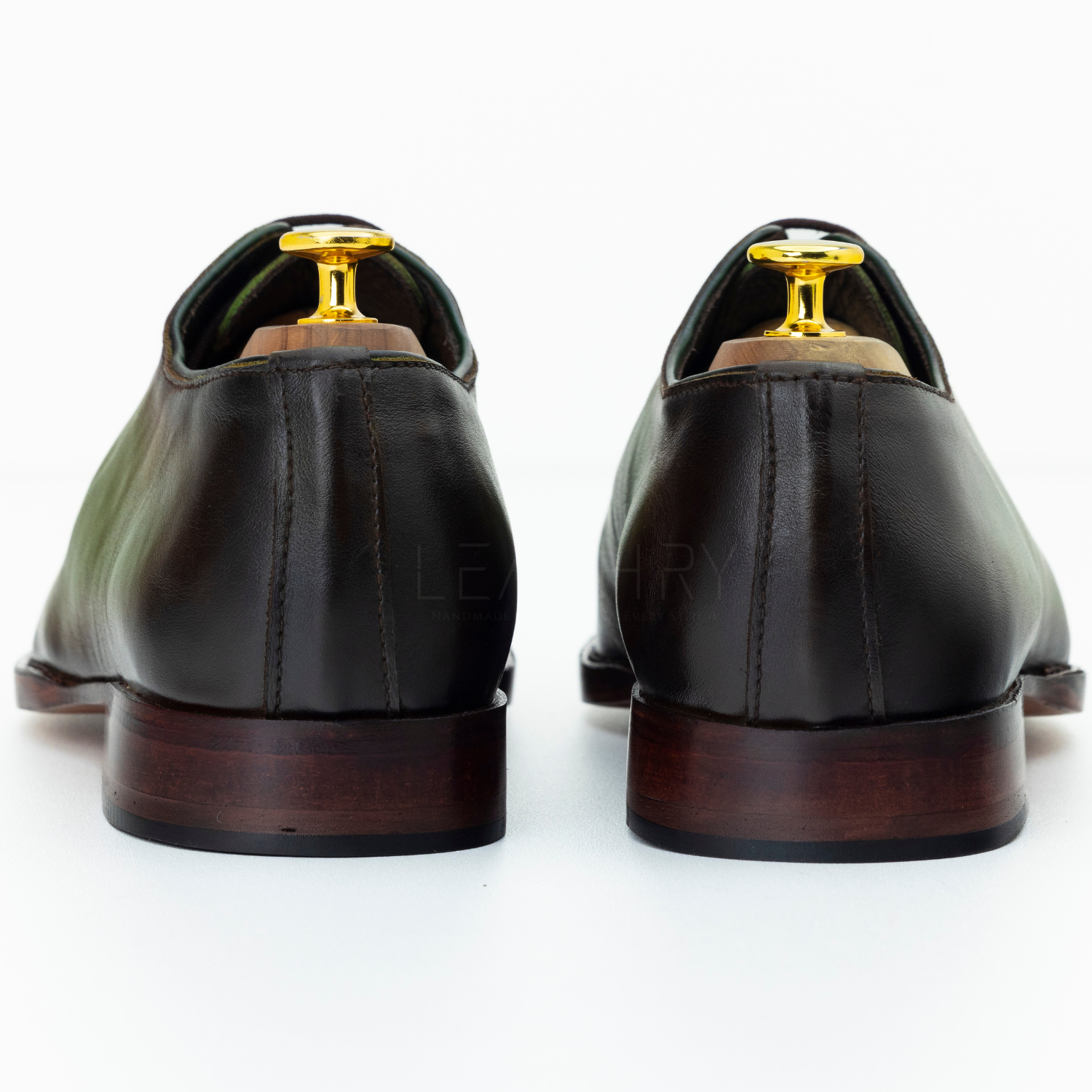 Pair of black leather shoes with gold accents on a white background