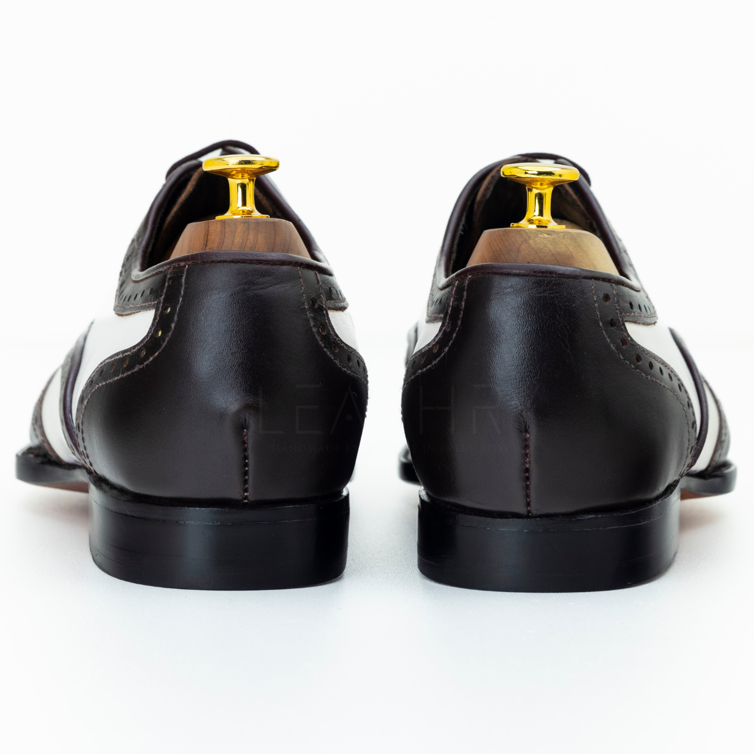 Black leather dress shoes with gold tips on a white background
