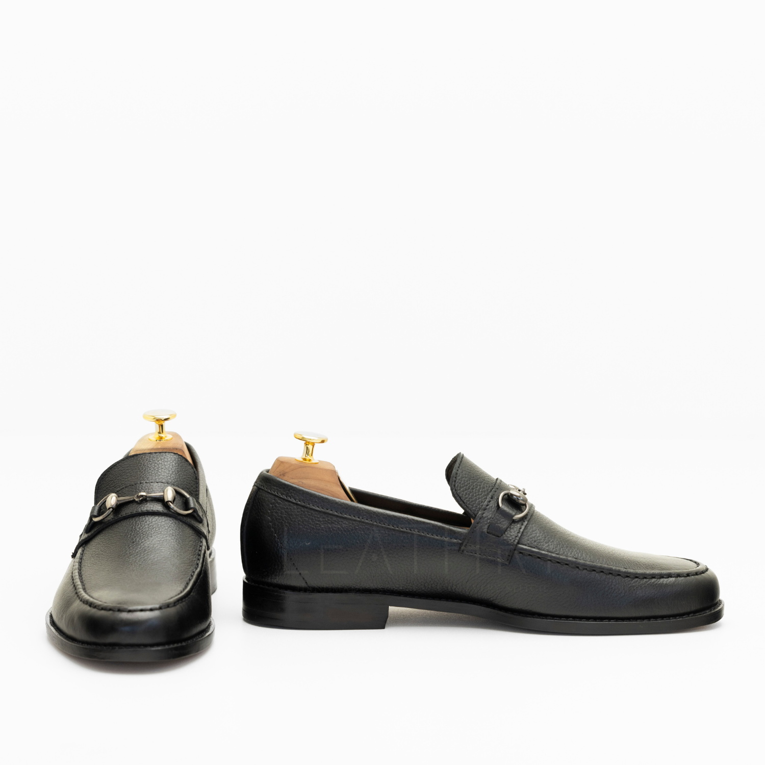 Pair of black leather loafers on a white background